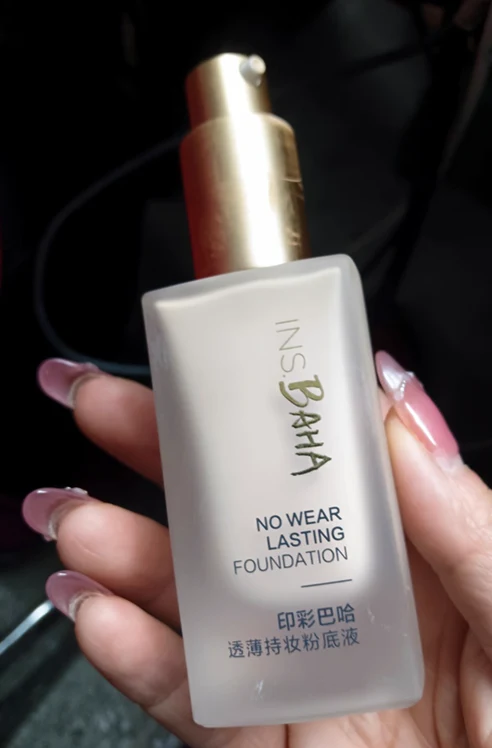 A hand holding a foundation bottle